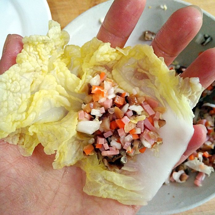 莲花娃娃菜&三鲜娃娃菜卷,取一片烫软的菜叶，包进拌好的馅料，两边折进来包起成菜卷。