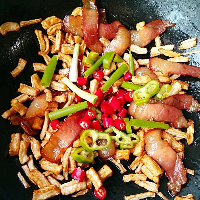 湘味萝卜干炒腊肉,然后加入杭椒，小米辣和小葱段，大火翻炒断生。