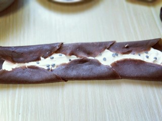 可可巧克力豆毛巾卷,将可可皮两边对折，如图。 之后再从另一端卷起来即可。