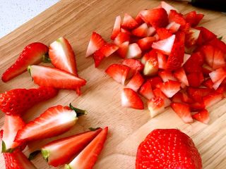 草莓奶油瑞士蛋糕卷,草莓切一些丁,再切几瓣带叶子的草莓瓣,用来做表面装饰。