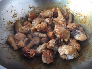 天津甘栗焖鸡,倒入焯过水的三黄鸡迅速翻炒，让糖色均匀的裹在鸡块上。