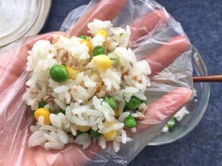豌豆玉米饭团,准备保鲜膜一块，将米饭舀入保鲜膜中包起来，用手捏成米饭团。
