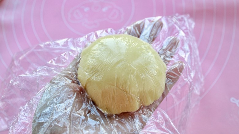 菠萝包,揭去上面的一层保鲜膜，把酥皮包裹在面团上，再拿掉上面的保鲜膜