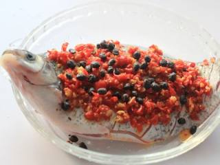 预热年夜菜---红红火火清蒸剁椒鱼,经过腌制的鱼用水冲洗干净，取一个蒸盘，把洗干净的鱼放在盘里，葱节放进鱼肚子里，剁椒与豆豉铺在鱼的表面