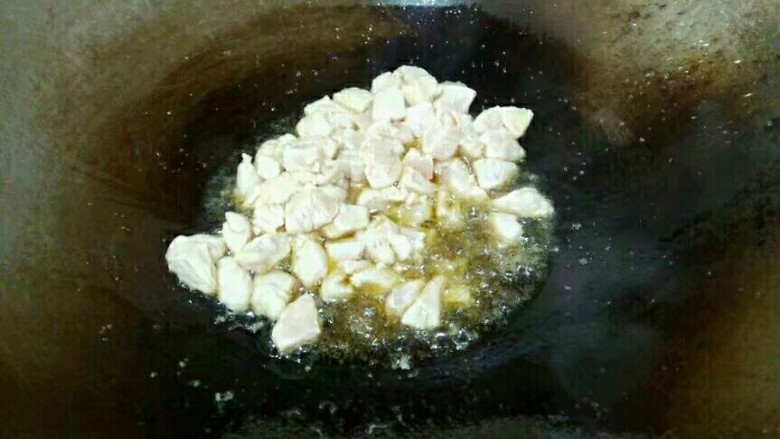 杏鲍菇炒鸡丁,油熟，倒入腌好的鸡丁，翻炒片刻。