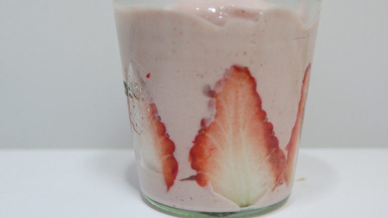 草莓奶酪布丁,倒入之前贴好草莓的杯子里。放入冰箱冷藏2个小时左右，完全凝固即可。