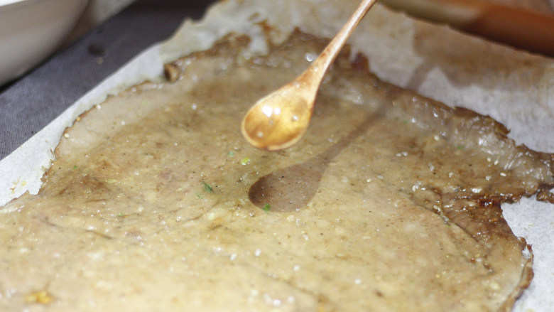 甜脆香酥的猪肉脯,完成第一次烤制的肉脯片从烤箱取出，将其翻面放置，刷上一层蜂蜜