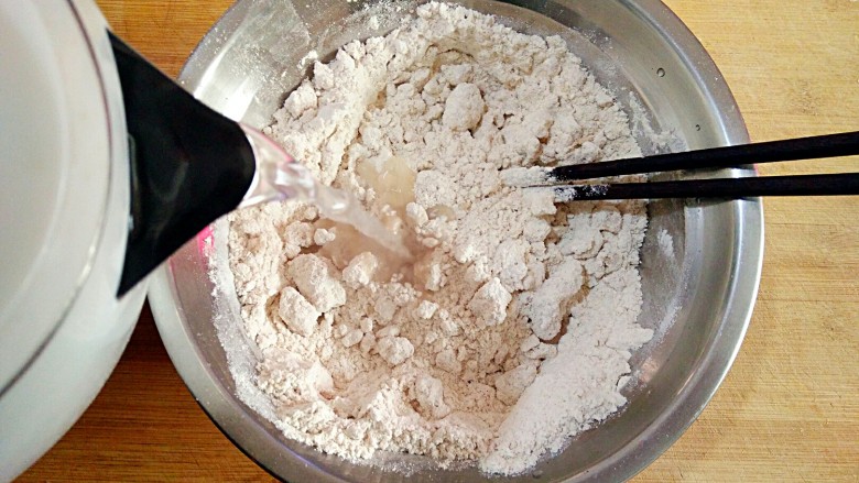 莜面栲栳栳,刚刚烧好的热开水分次倒在莜麦粉上，用筷子搅拌成絮状。