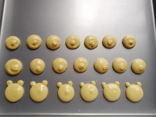 小熊柠檬蛋黄饼干,先用大份蛋糊在不粘烤盘上挤上圆形，再用小份蛋糊在圆形上方两侧挤上两个小圆点，这样小熊胚形就出来了；
