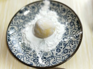 爆汁芝士南瓜球,包好的芝士南瓜球放生粉盘子里，滚上一层粉。