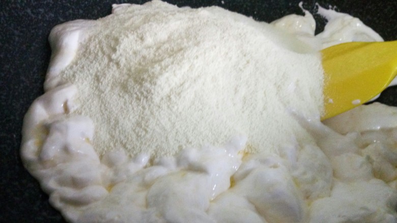 红枣花生牛扎糖,迅速倒入奶粉，用硅胶铲让棉花糖和奶粉翻拌融合。