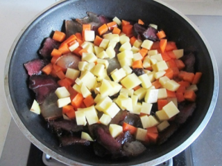 土豆腊肉焖饭,翻炒片刻后，下土豆丁翻炒。