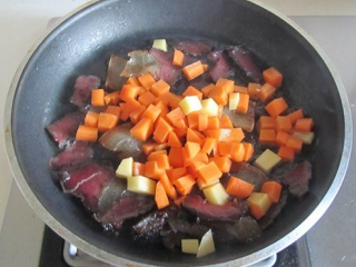 土豆腊肉焖饭,等腊肉肥肉部分变得透明，表面微微发焦，下胡萝卜丁翻炒。