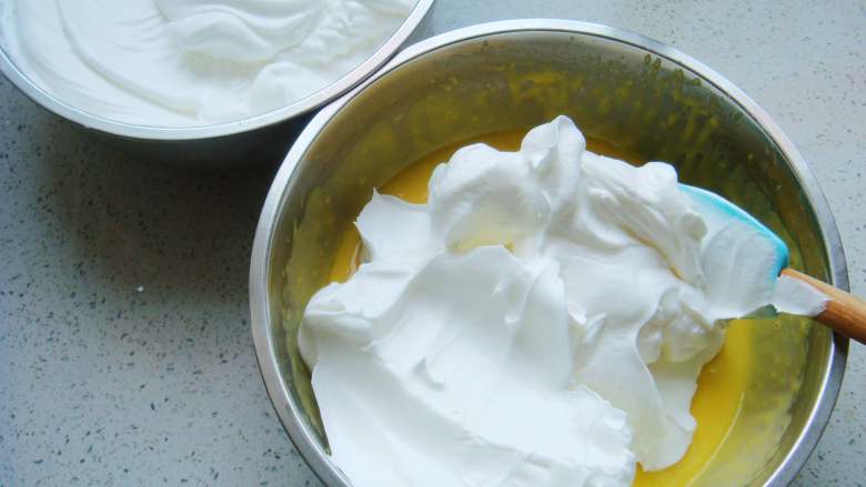 红枣葡萄干蛋糕杯,把打好的蛋白分一半倒入蛋黄糊糊里。呈“J”字形翻拌，不可划圈避免消泡。