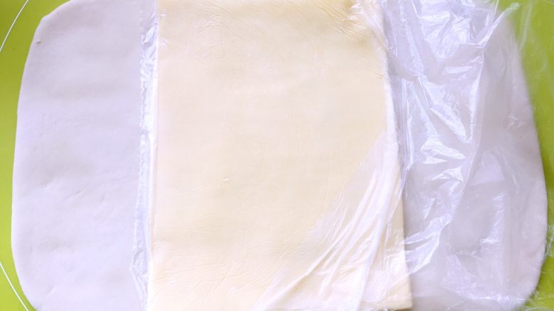 白富美跟粉小妹,取出冷冻的黄油片，用简单裁开保鲜袋，将黄油片铺在面片中间