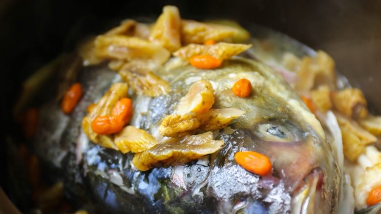 天麻鱼头炖豆腐,接着将鱼头转到炖锅中，倒入天麻枸杞水；