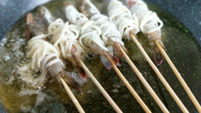 #春节家宴#-面条缠虾,起油锅，油温8成时加入缠好面条的虾。