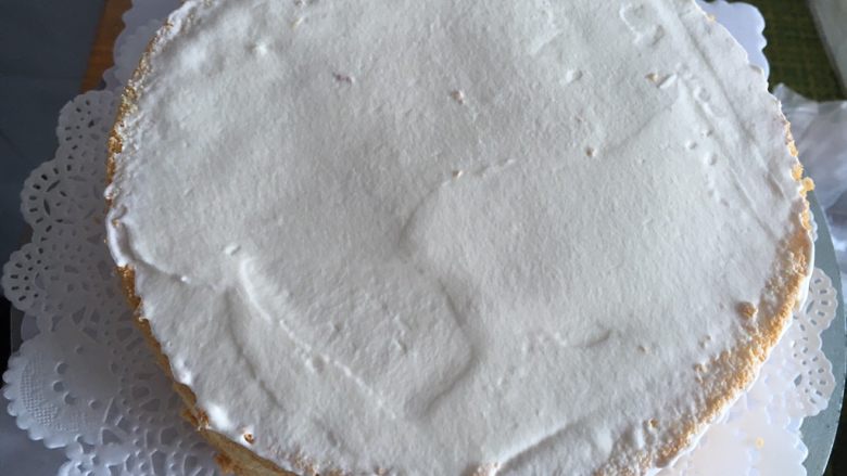 戚风淋面生日蛋糕,先把一层的蛋糕胚摆放在蛋糕转台正中央，抹上奶油