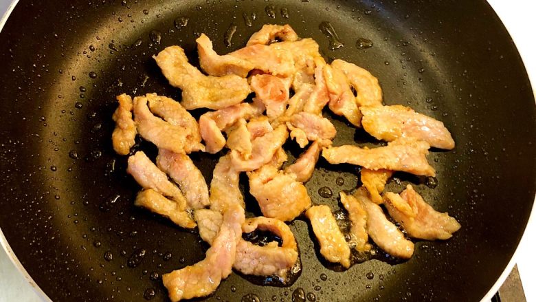 手撕杏鲍菇炒肉片,热锅下油，爆炒猪肉片至变色后取出待用。