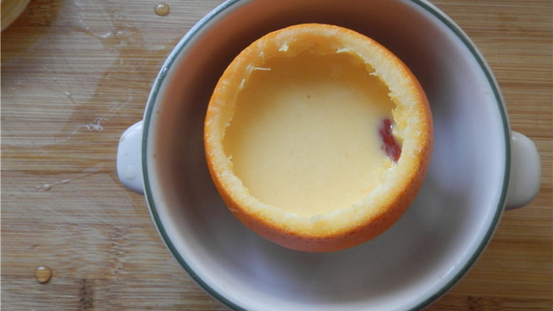 国橙蒸枸杞蛋,橙子放入小碗，倒入牛奶香橙蛋液至八分满。