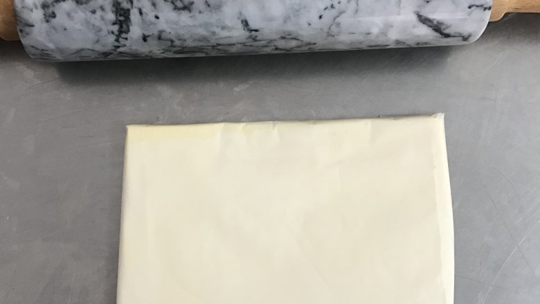 网红脏脏包,将黄油取出，切成小块状，用油纸包好，擀成长方形的薄片，大概7mm厚。
