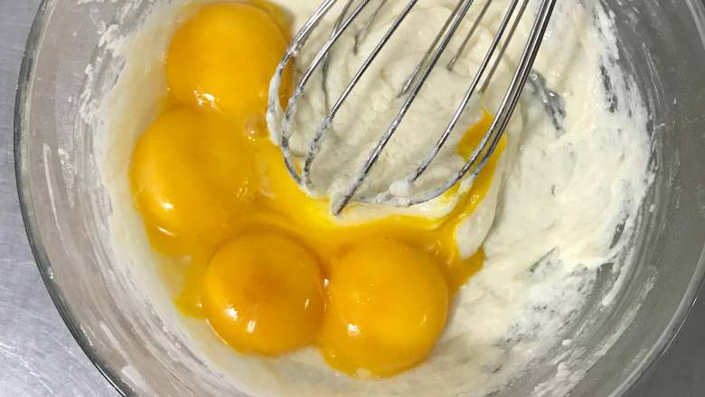 双色蛋糕卷,将蛋黄放入面糊中，继续用手动打蛋器搅拌均匀，成细腻的蛋黄糊。
