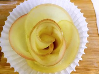 百变水果+苹果玫瑰花派,一个苹果玫瑰花就做好啦，刚卷好的玫瑰花比较拘谨，像一个未开放的花苞，你要用手轻轻的向外拉，让花瓣打开一些，不要太用力，以免把卷好的玫瑰花扯散了。调整到你想要的形状就可以了。