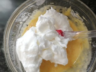 南瓜蒸糕,取一大勺蛋白放入蛋黄糊里，用翻拌的手法进行混合均匀