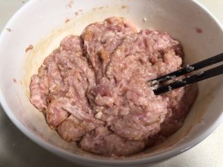Q弹劲道的山药肉丸子,准备一个大的容器放入肉糜 ，加入调味品，用筷子顺时针方向搅拌肉糜。