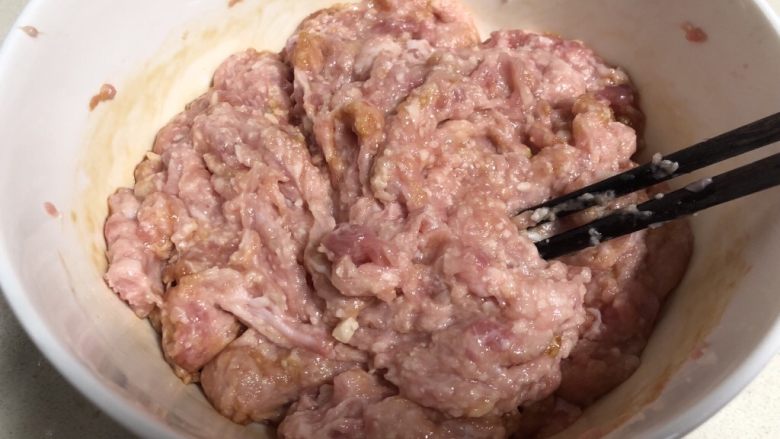 Q弹劲道的山药肉丸子,准备一个大的容器放入肉糜 ，加入调味品，用筷子顺时针方向搅拌肉糜。