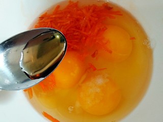 秋葵两吃,鸡蛋打进容器中，加适量胡萝卜碎，盐，和一小勺料酒打散。