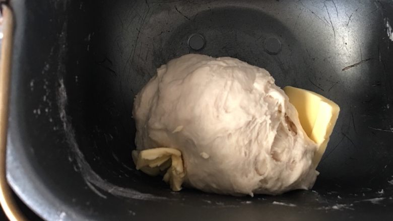 椰蓉泡浆面包,待面团基本光滑后放入软化的黄油继续和面