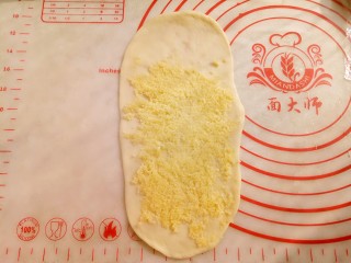 椰蓉小餐包,取15克椰蓉均匀铺在牛舌型面饼上。（如图留出1/5空余）
