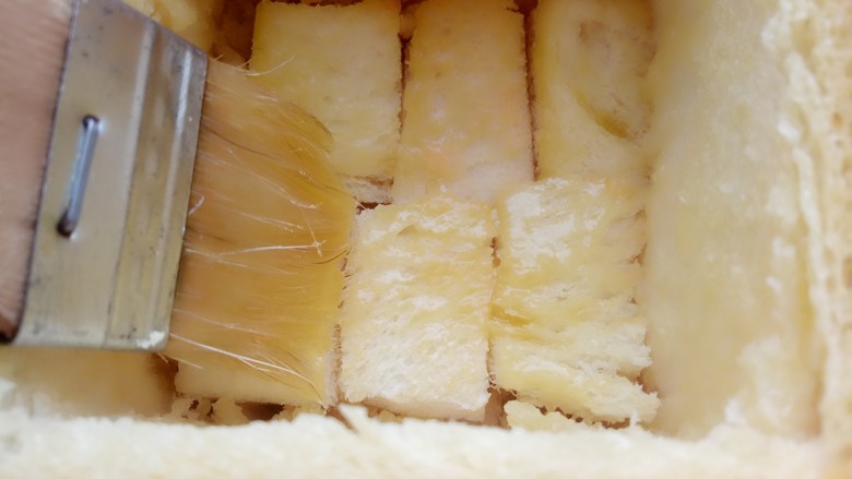 鲜虾厚多士,用刷子粘黄油蜂蜜液把吐司的内壁刷一遍，摆上一层切好的吐司块，再刷一层黄油蜂蜜液。
