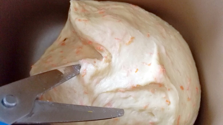 胡萝卜奶酪小餐包～一次发酵,继续放入面包机，开启和面程序，期间用剪刀在面团上剪一下，大约剪十下左右，为了面包更好的排气