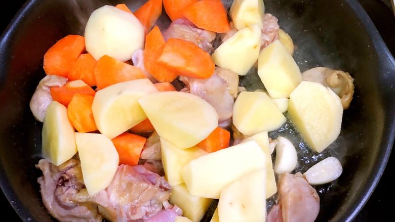 土豆烧鸡,倒入土豆和胡萝卜，大火翻炒3分钟左右。