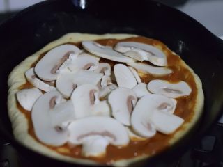 铸铁锅基础披萨,铺上切片的蘑菇。