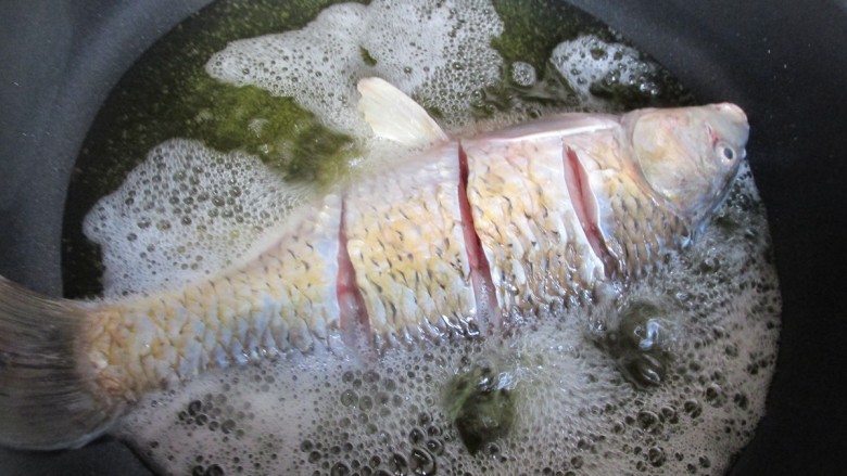 糖醋鲤鱼,油七成热时下入鲤鱼炸制。