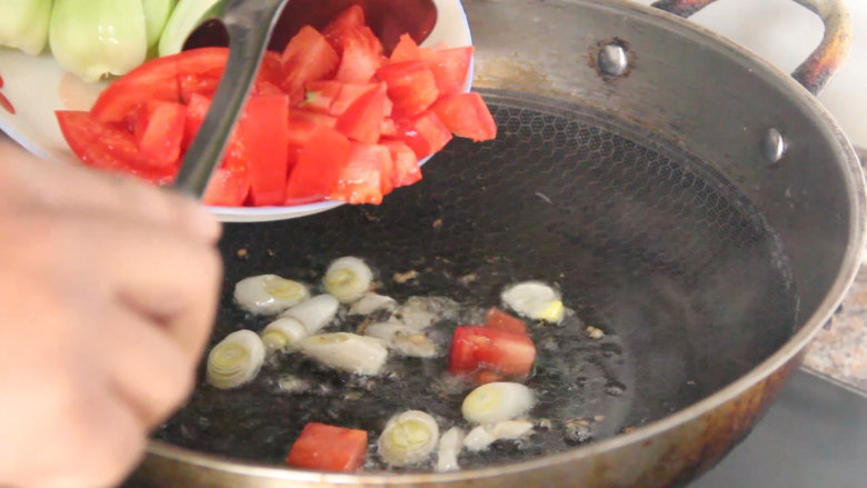 家常炒面,锅烧油，先下入葱炒香后再下入西红柿丁翻炒。