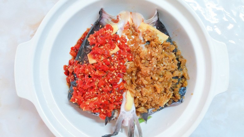 双椒焗鱼头,把调好味的剁辣椒和野山椒分别倒入鱼头的两边！