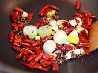 辣子鸡丁,锅中留少许底油烧热，小火放入干辣椒、干花椒和葱姜蒜炒香。