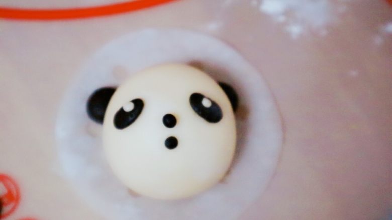 熊猫豆包,然后放一个小小的白色面球做眼仁部分，嘴巴和鼻子是两个黑色小球球，如图所示不需要太大