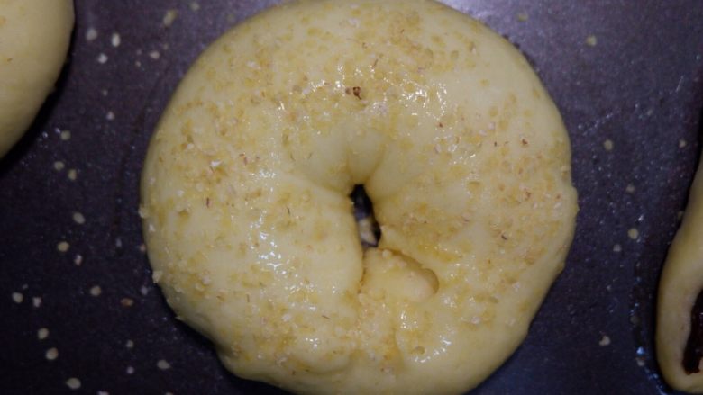 小麦胚芽贝果豆沙面包,取出刷鸡蛋液，中间撒上小麦胚芽点缀