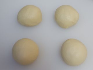 豆沙面包卷,平均分成4份，滚圆，盖上保鲜膜松弛10分钟。