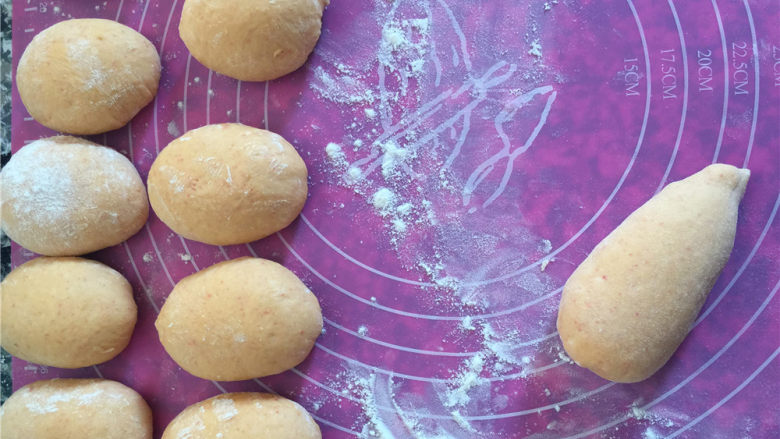 胡萝卜椰蓉卷儿小餐包,分割成16等分，取其中的一块，将它揉搓成圆锥体的样子。