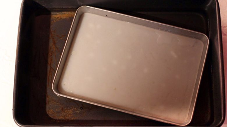 陕西小吃—凉皮,凉皮呈透明状起些小白泡就表明熟透了，取出放入事先准备好的装了凉水的深烤盘中浸泡五分钟。