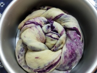 紫薯辫子面包,将辫子盘起来，尾部放在面团底部，压紧，放入6寸蛋糕模具中。放入烤箱用38度发酵模式进行二发，约半小时，至面团涨到模具9分满。