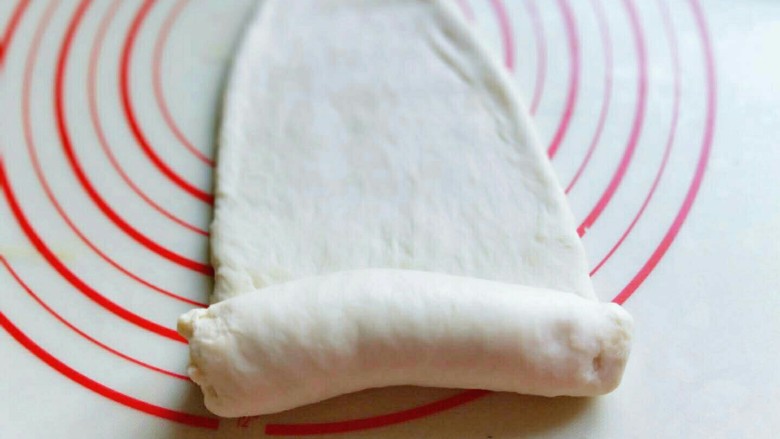 原味水立方吐司面包,取一块面团用擀面杖擀长舌状，再卷起来，从上往下卷，依次做完。
