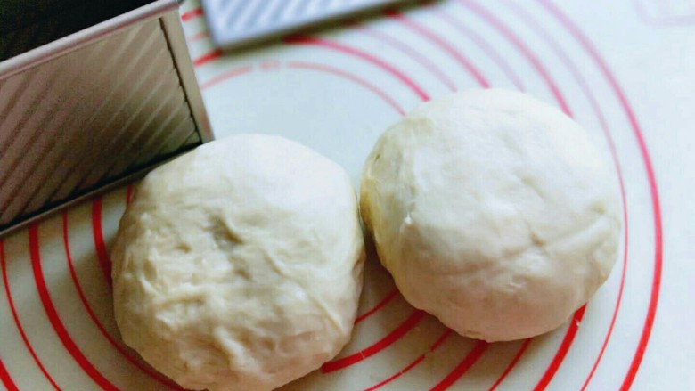 原味水立方吐司面包,将面团从面包机中取出，分成2等份，揉圆，盖上保鲜膜松弛10分钟。