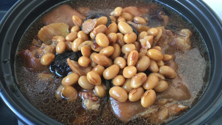 美容养颜养生菜 黄豆煲猪手,将步骤18一部分的猪手黄豆连同汤汁放入砂锅里。
